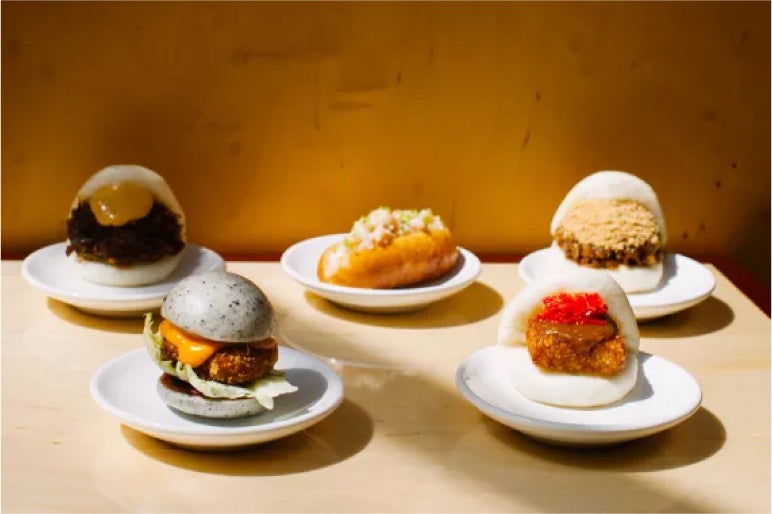 Assorted bao buns with creative fillings, served on white plates at Bao Borough Market, showcasing unique flavors and texture
