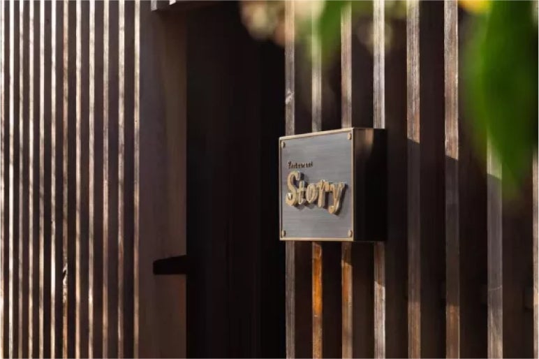 Wooden entrance to Restaurant Story, featuring a gold-engraved sign, inviting guests into its unique culinary experience