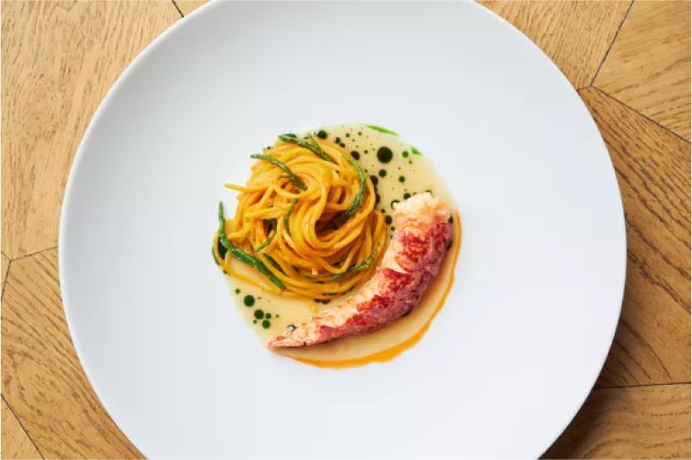 Lobster and spaghetti with herb-infused sauce, elegantly plated to combine fresh seafood flavors and delicate pasta artistry