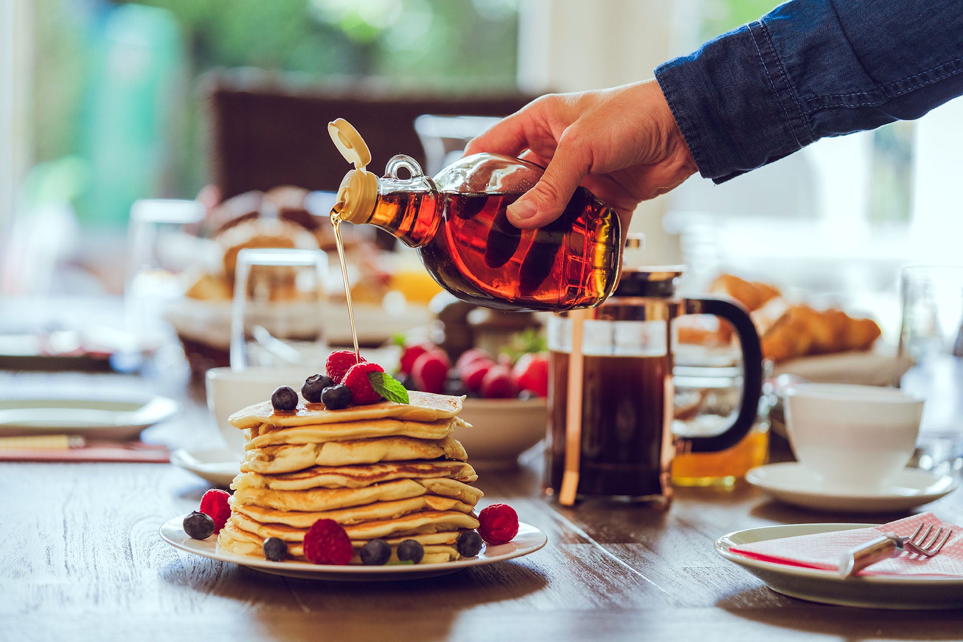 a stack of pancakes being drizzled with maple syrup