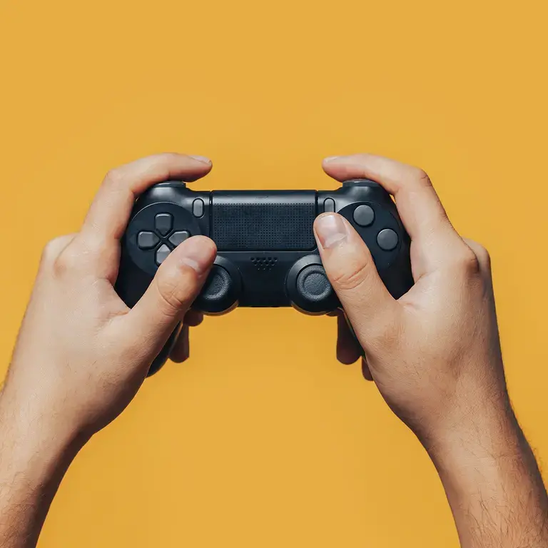 Two hands holding a videogame controller on a yellow background