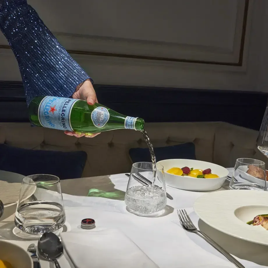 S.Pellegrino being poured at a dining table.
