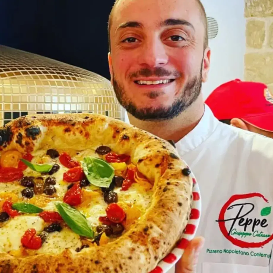Peppe Cutraro holding up one of his pizzas