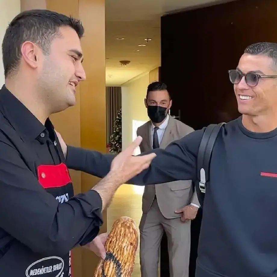 Chef Burak Özdemir and footballer Cristiano Ronaldo greeting each other.