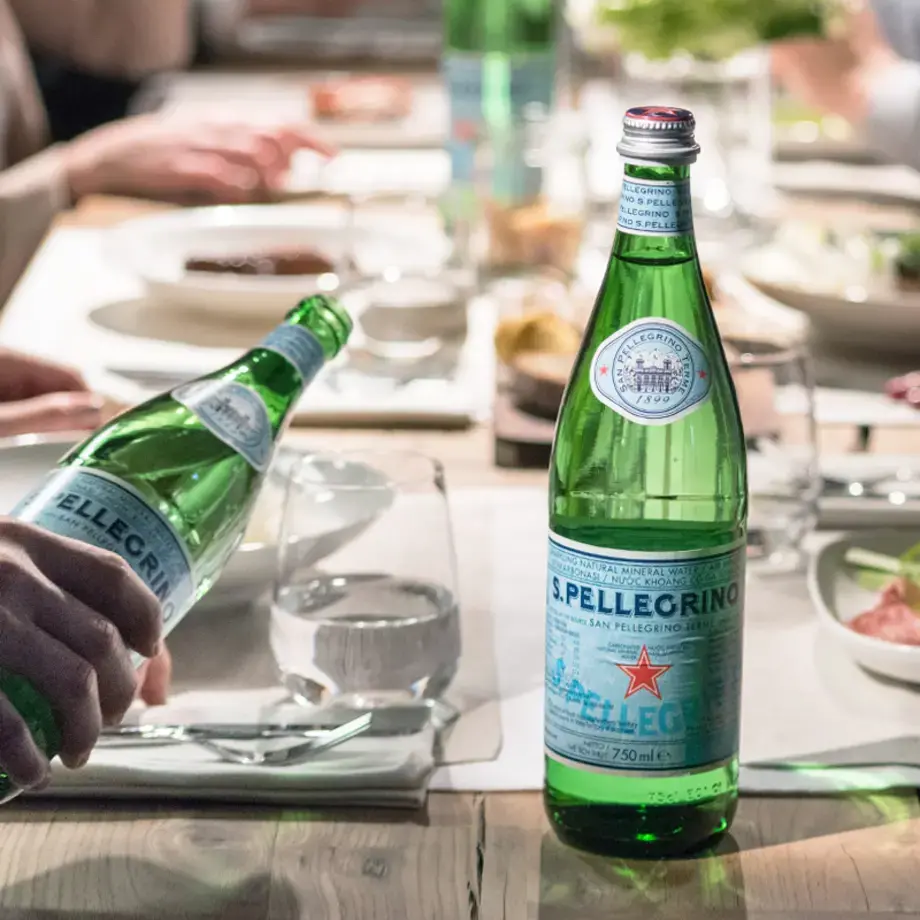 Table of people with S. Pellegrino water bottles.