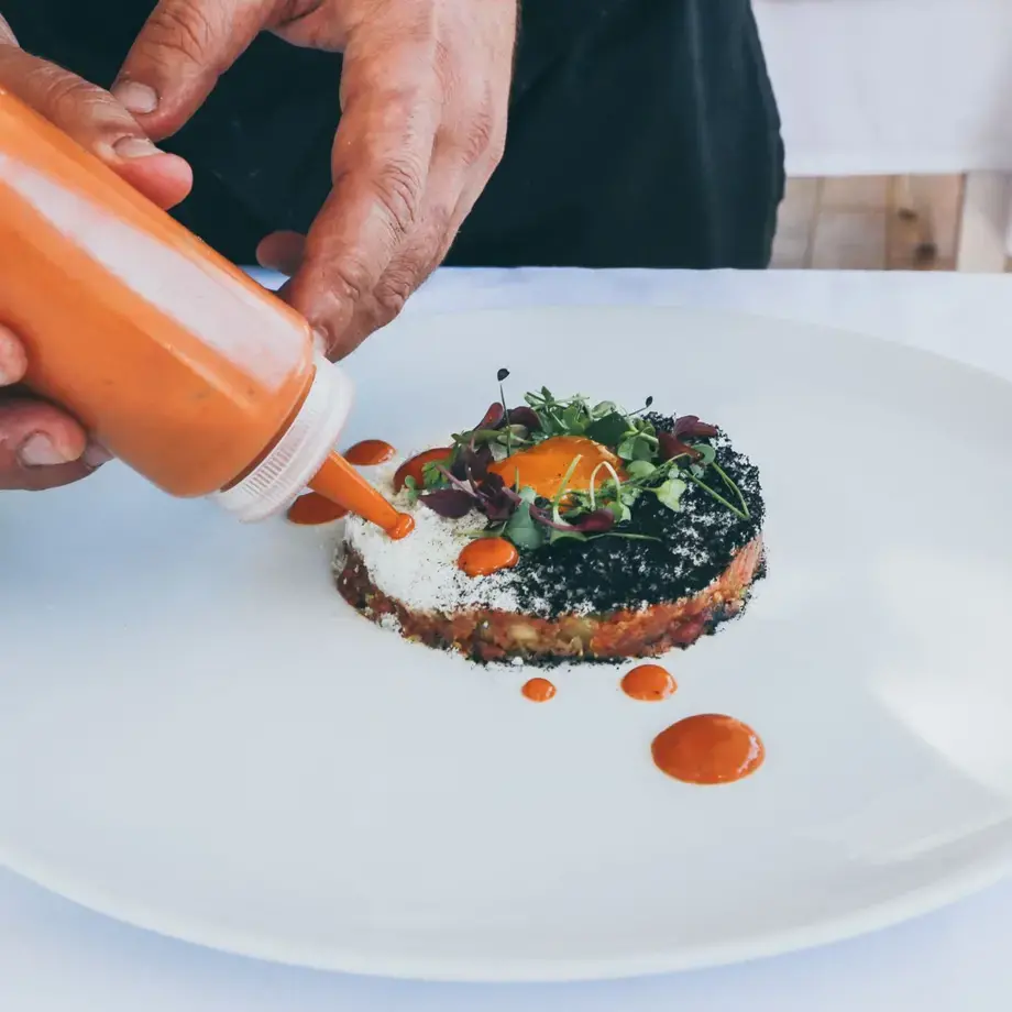 a chef's hands adding final plating touches