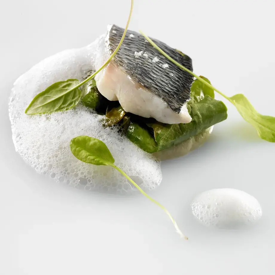 Sea bass, celeriac purée, wild sorrel and smoked sauce with shellfish by Mauro Colagreco.