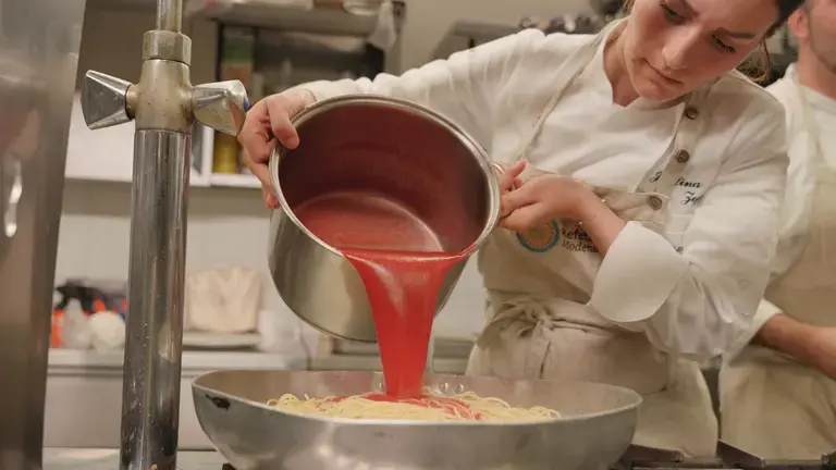 Chef seasoning spaghetti with tomato