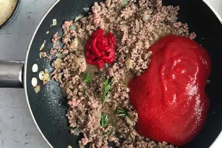 ground beef and tomato paste in a pan