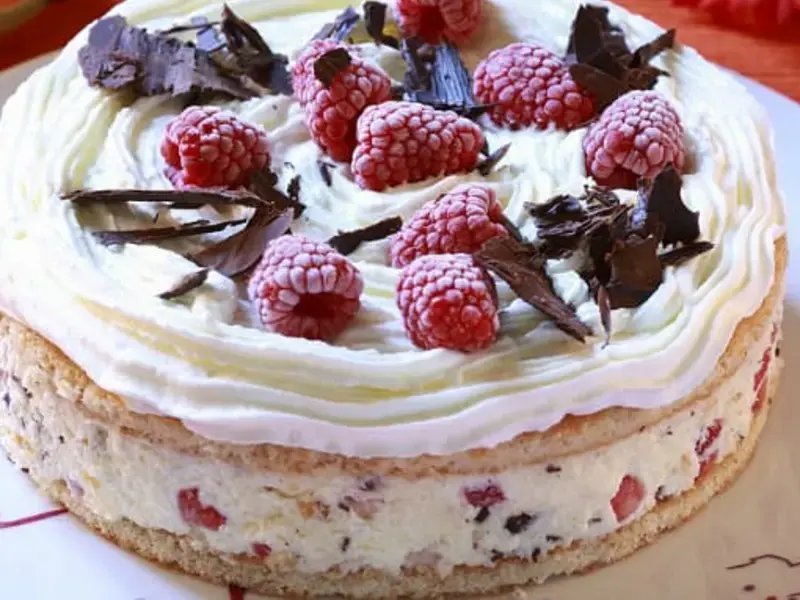 Ice cream cake topped with raspberries and chocolate.
