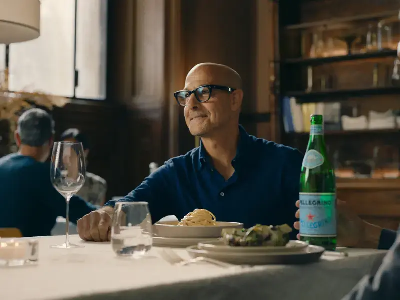 Stanley Tucci at a table with San Pellegrino