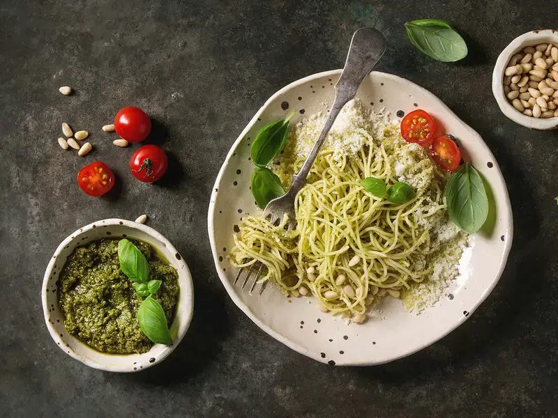 Classic italian spaghetti pasta with pesto sauce, pine nuts, olive oil and fresh basil