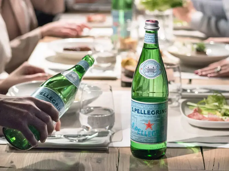 Table of people with S. Pellegrino water bottles.