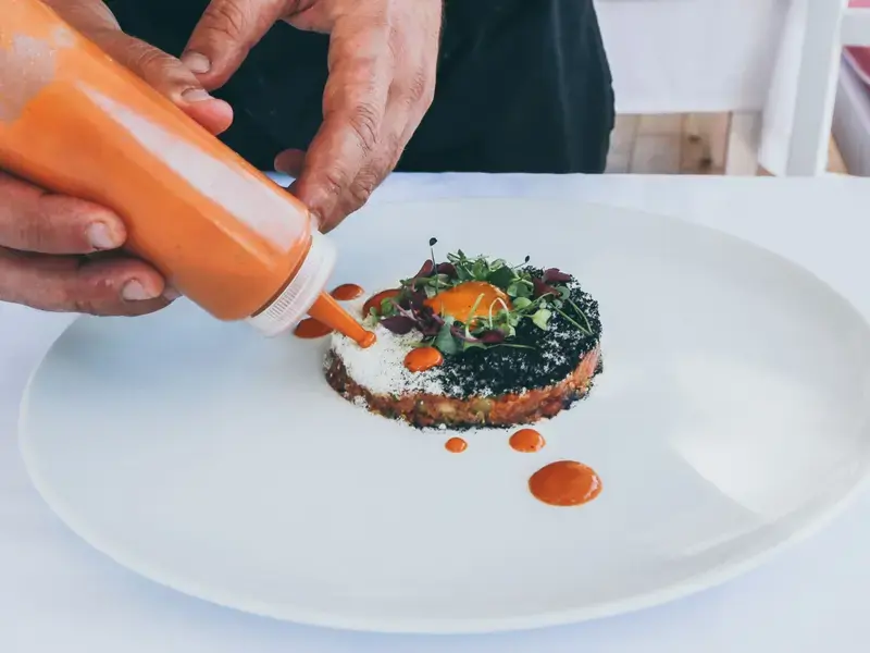 a chef's hands adding final plating touches